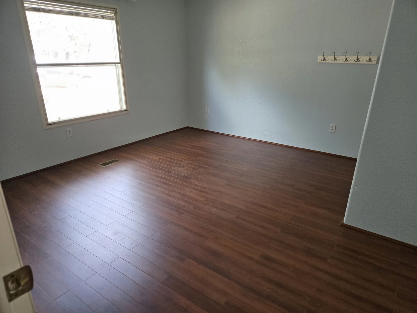 An empty room with wood flooring after furniture and belongings have been removed