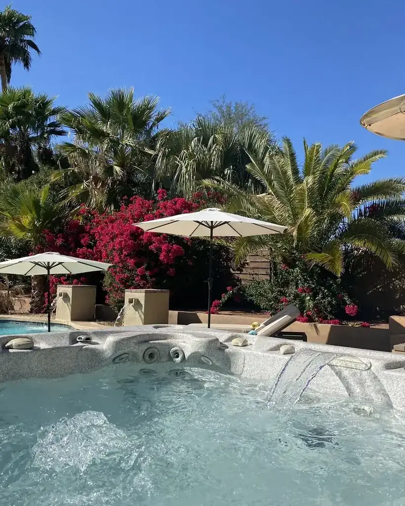 A hot tub running beside a patio heater, framed by palms
and bougainvillea at a Scottsdale rental